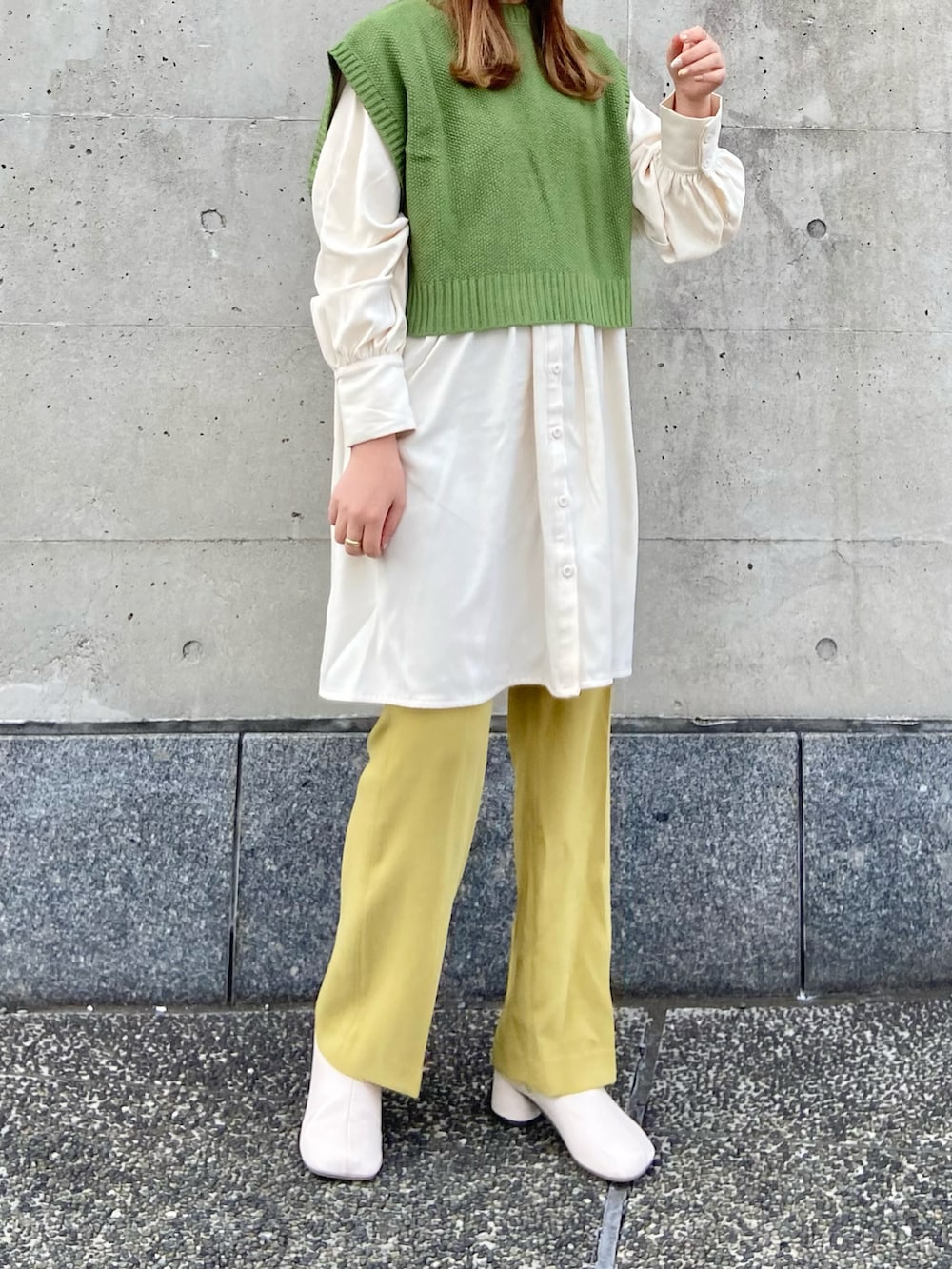 グリーン系のベスト、イエロー系のその他パンツ、ホワイト系のシャツワンピースを着用したレディースの春コーディネートの2枚目の写真