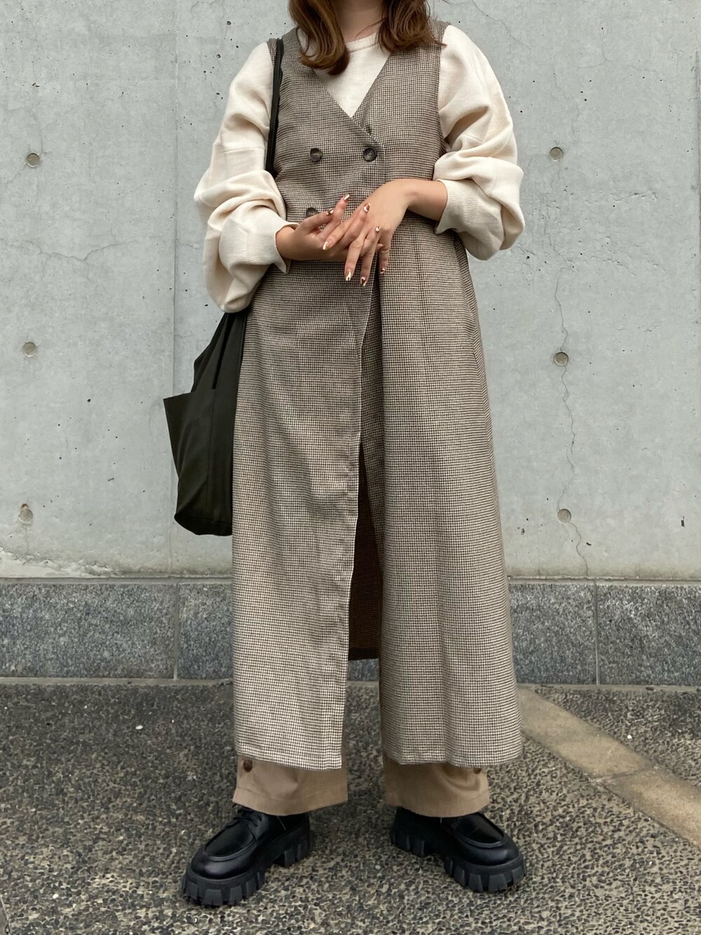 ブラウン系のベスト、ベージュ系のその他パンツ、グリーン系のショルダーバッグを着用したレディースの冬コーディネートの4枚目の写真