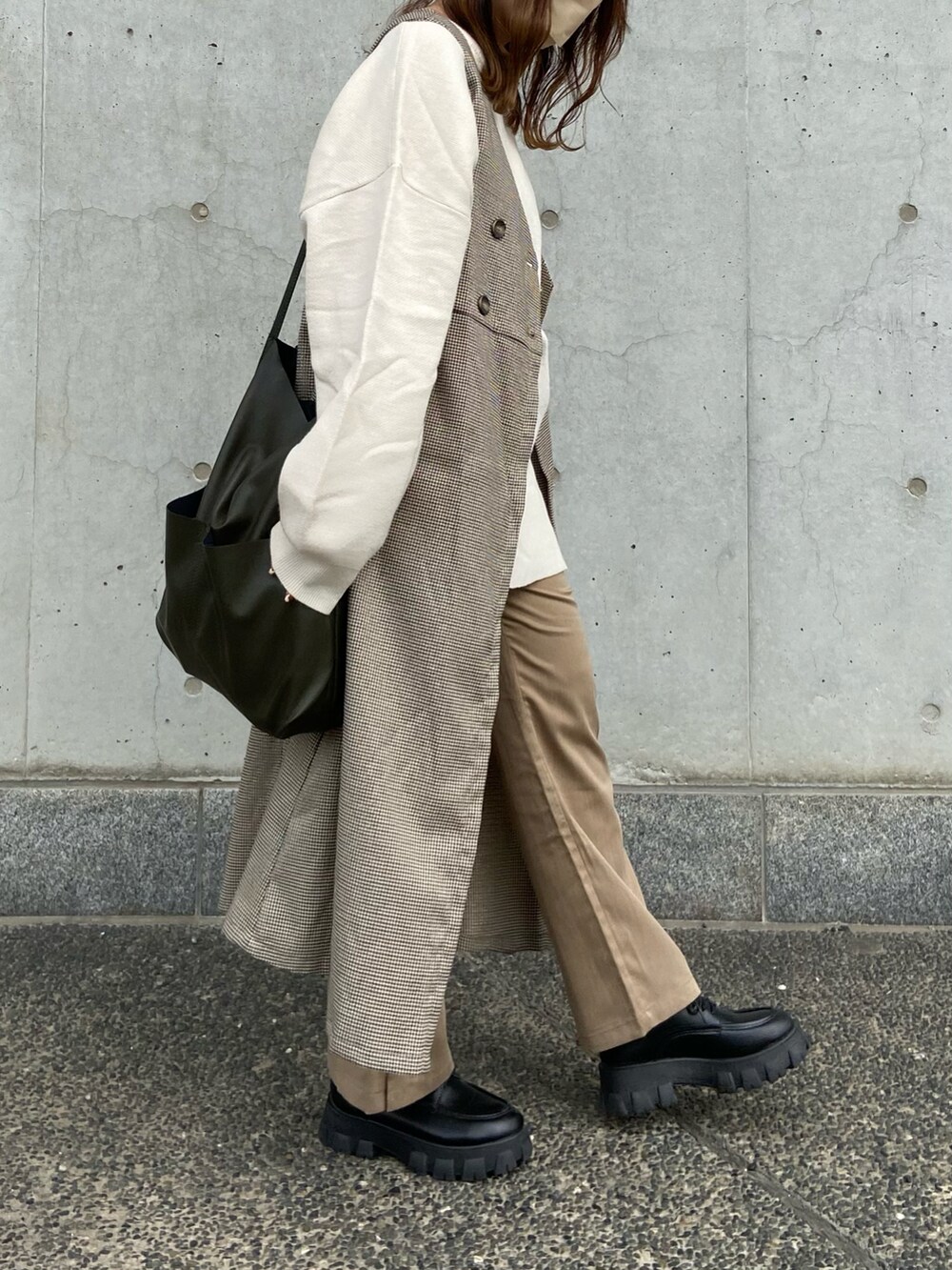 ブラウン系のベスト、ベージュ系のその他パンツ、グリーン系のショルダーバッグを着用したレディースの冬コーディネートの2枚目の写真