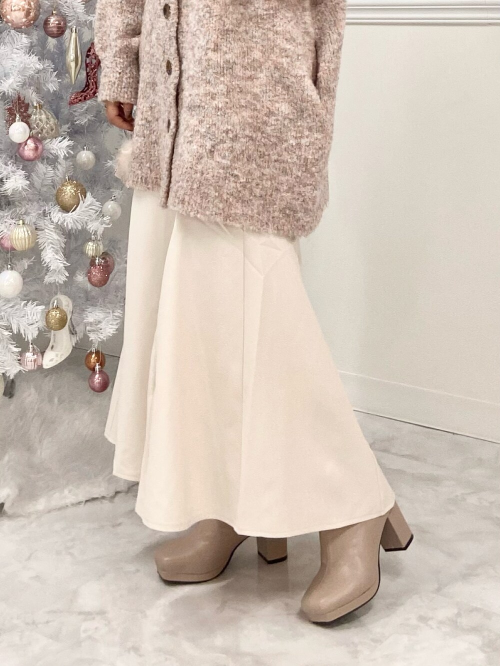 ピンク系のカーディガン/ボレロ、ホワイト系のスカート、ベージュ系のブーツを着用したレディースの冬コーディネートの3枚目の写真