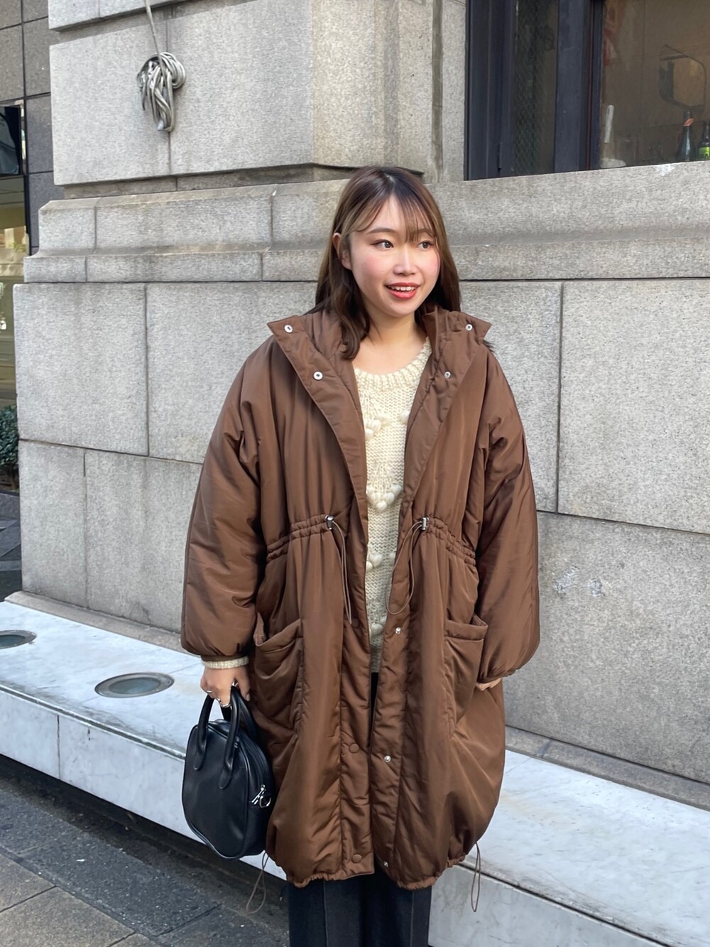 ブラック系のデニムパンツ、ブラウン系のダウンジャケット/コート、ホワイト系のニット/セーターを着用したレディースの秋コーディネートの3枚目の写真