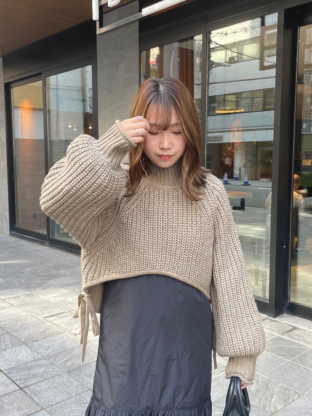 ベージュ系のニット/セーター、ブラック系のワンピース/ドレス、ホワイト系のブーツを着用したレディースの秋コーディネートの5枚目の写真