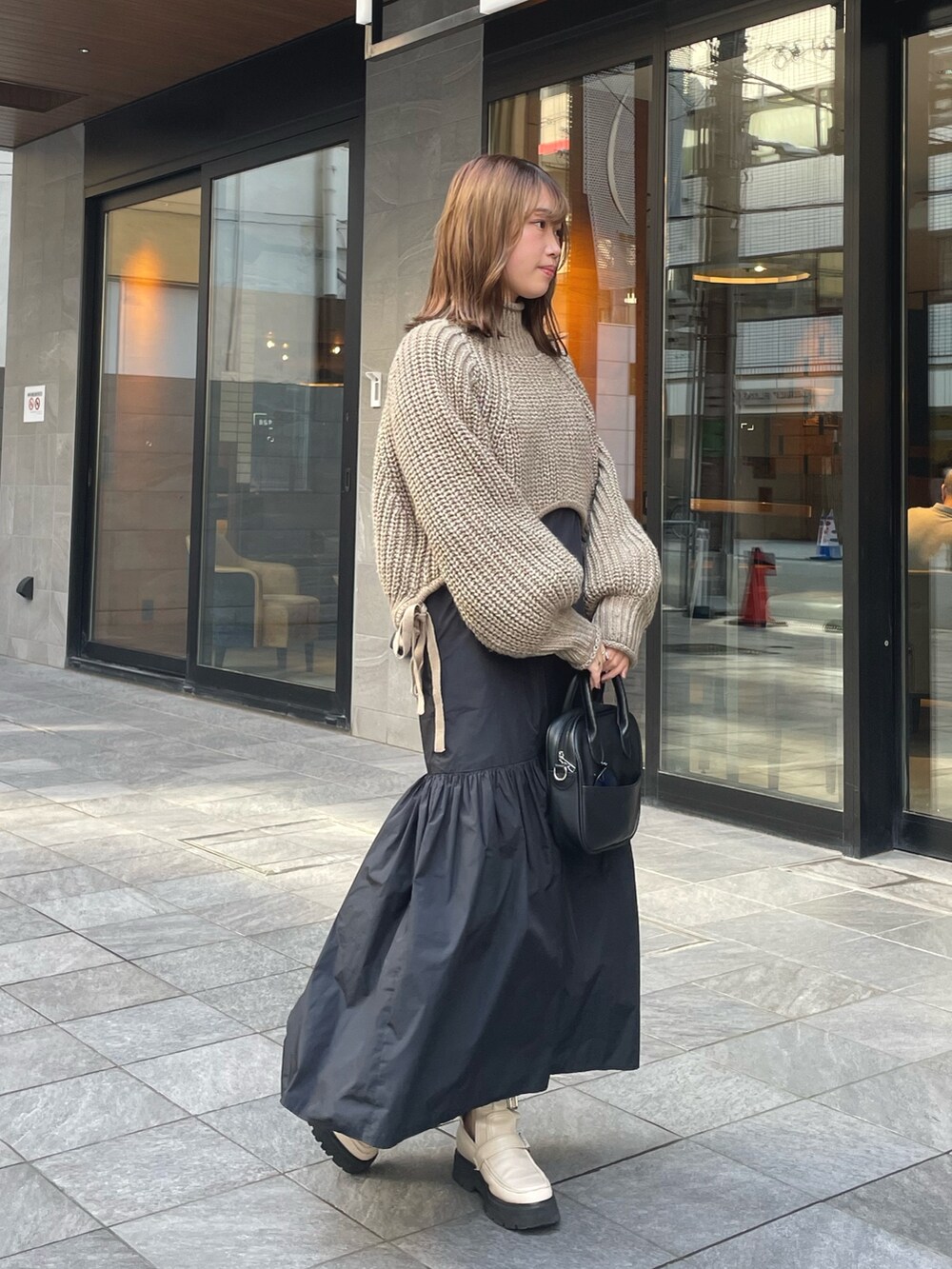 ベージュ系のニット/セーター、ブラック系のワンピース/ドレス、ホワイト系のブーツを着用したレディースの秋コーディネートの2枚目の写真