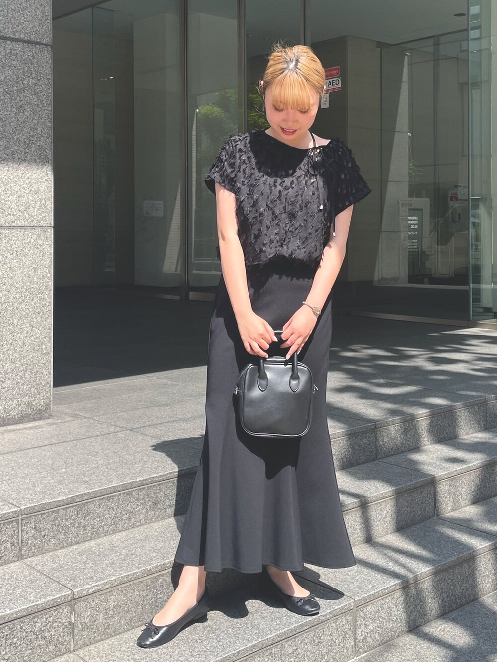 ブラック系のシャツ/ブラウス、ブラック系のスカート、ブラック系のメガネを着用したレディースの春コーディネートの2枚目の写真