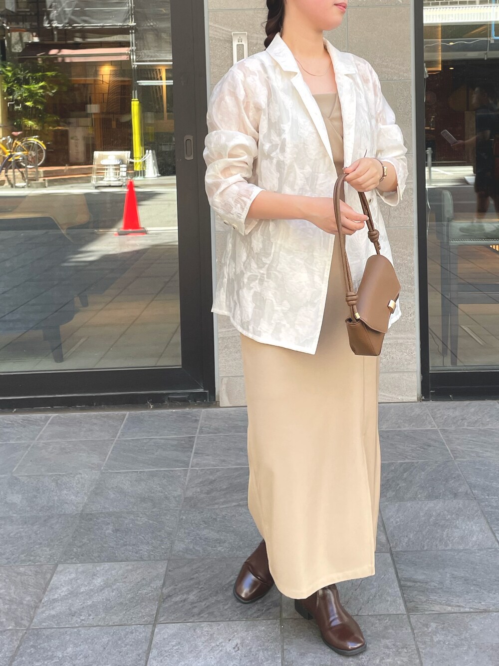 ホワイト系のテーラードジャケット、ベージュ系のドレスを着用したレディースの秋コーディネートの2枚目の写真