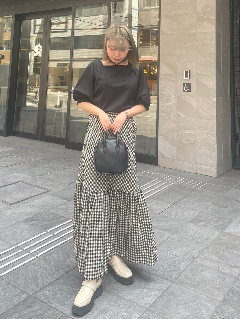 ブラック系のTシャツ/カットソー、ホワイト系のブーツ、ブラック系のスカートを着用したレディースの春コーディネートの2枚目の写真