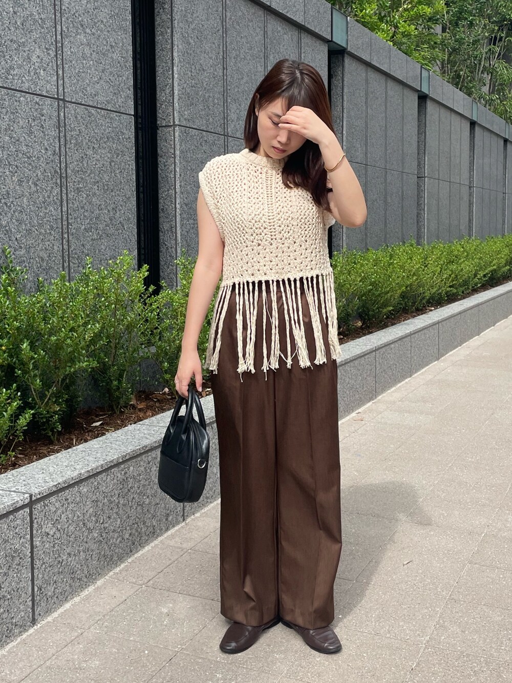 ブラウン系のスラックス、ベージュ系のベストを着用したレディースの夏コーディネートの2枚目の写真