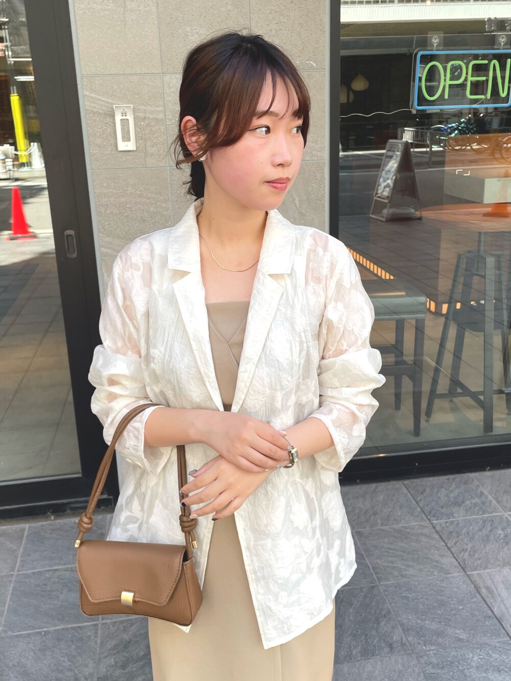 ホワイト系のテーラードジャケット、ベージュ系のドレスを着用したレディースの秋コーディネートの4枚目の写真