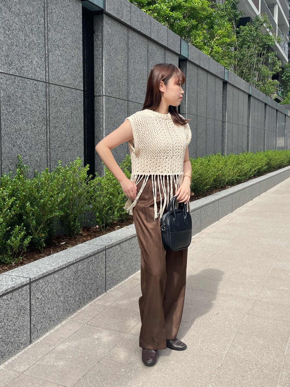 ブラウン系のスラックス、ベージュ系のベストを着用したレディースの夏コーディネートの4枚目の写真