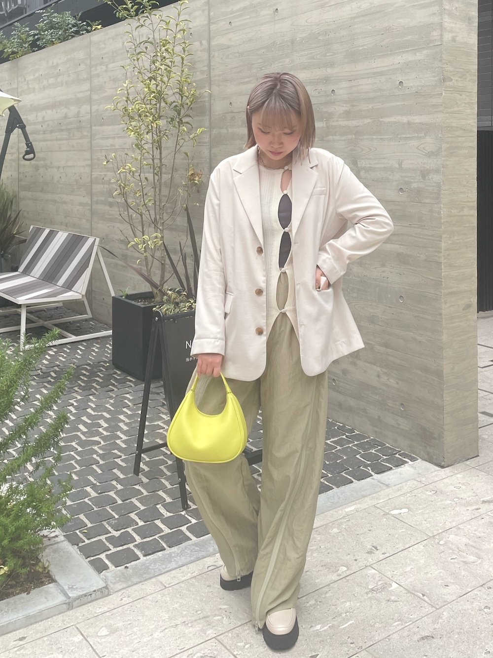 ベージュ系のパンツ、ホワイト系のブーツ、イエロー系のバッグを着用したレディースの春コーディネートの3枚目の写真