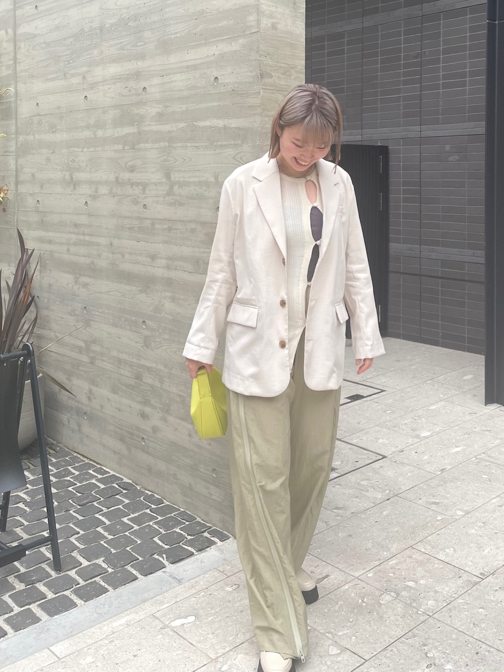 ベージュ系のパンツ、ホワイト系のブーツ、イエロー系のバッグを着用したレディースの春コーディネートの2枚目の写真