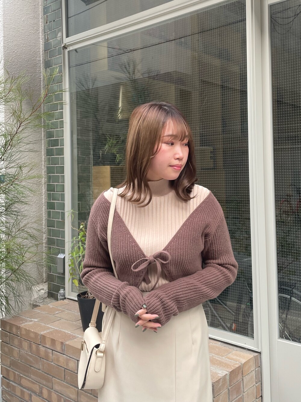 ホワイト系のスカート、ベージュ系のニット/セーター、ブラウン系のニット/セーターを着用したレディースの秋コーディネートの3枚目の写真