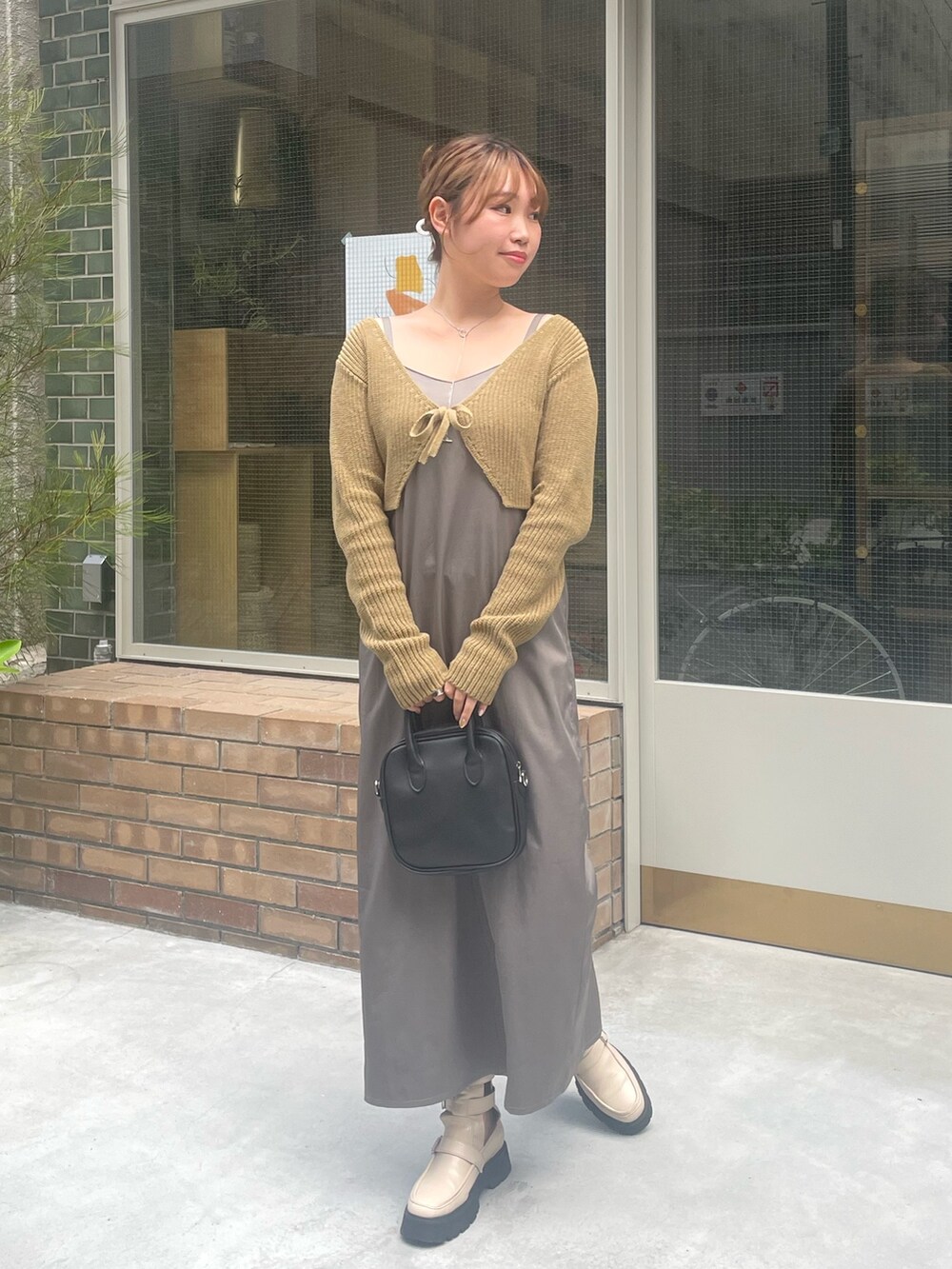 グリーン系のニット/セーター、ホワイト系のブーツを着用したレディースの夏コーディネートの2枚目の写真