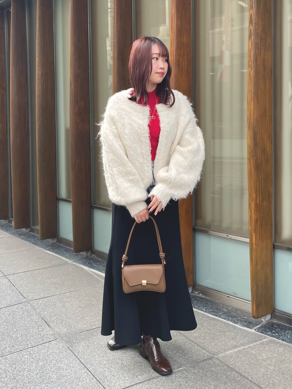レッド系のニット/セーター、ホワイト系のカーディガン/ボレロを着用したレディースの冬コーディネートの2枚目の写真