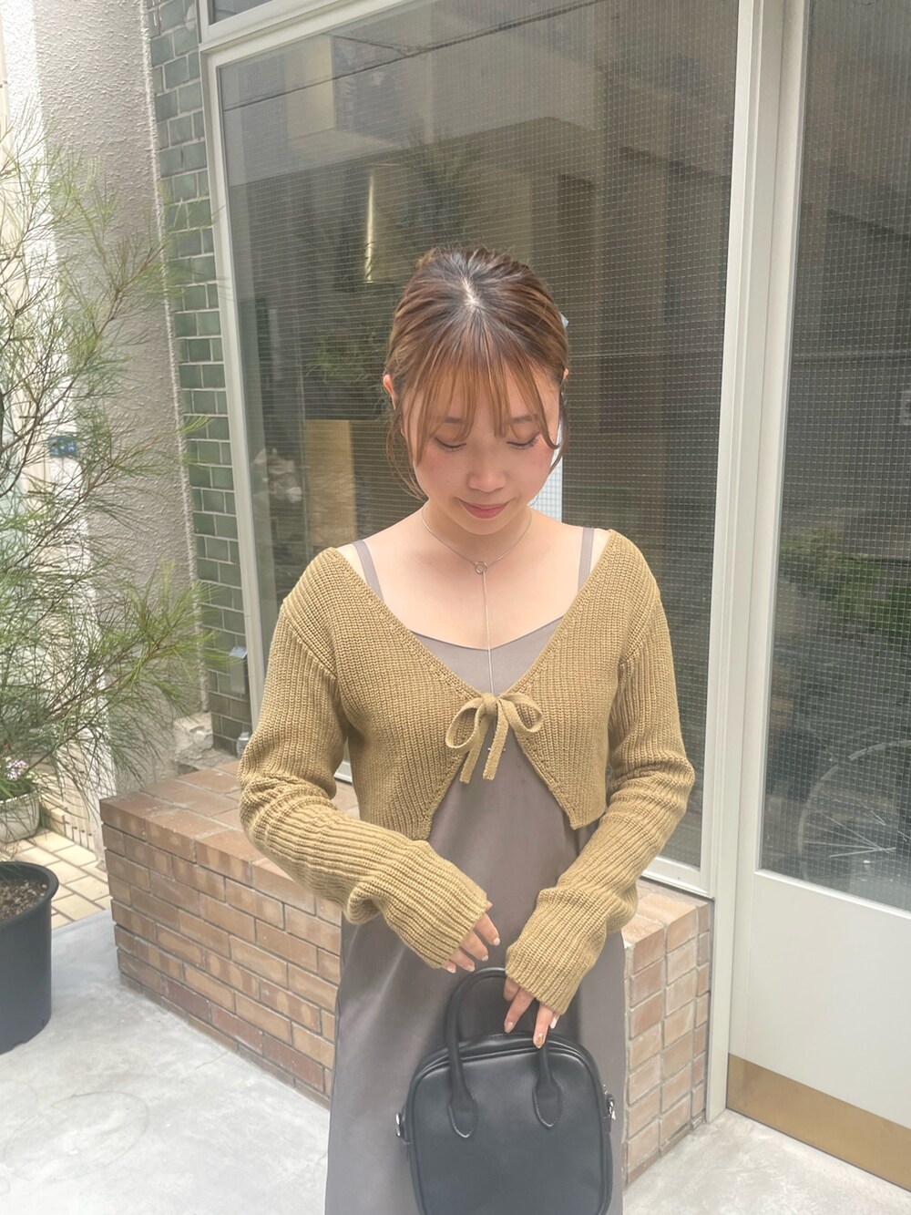 グリーン系のニット/セーター、ホワイト系のブーツを着用したレディースの夏コーディネートの3枚目の写真