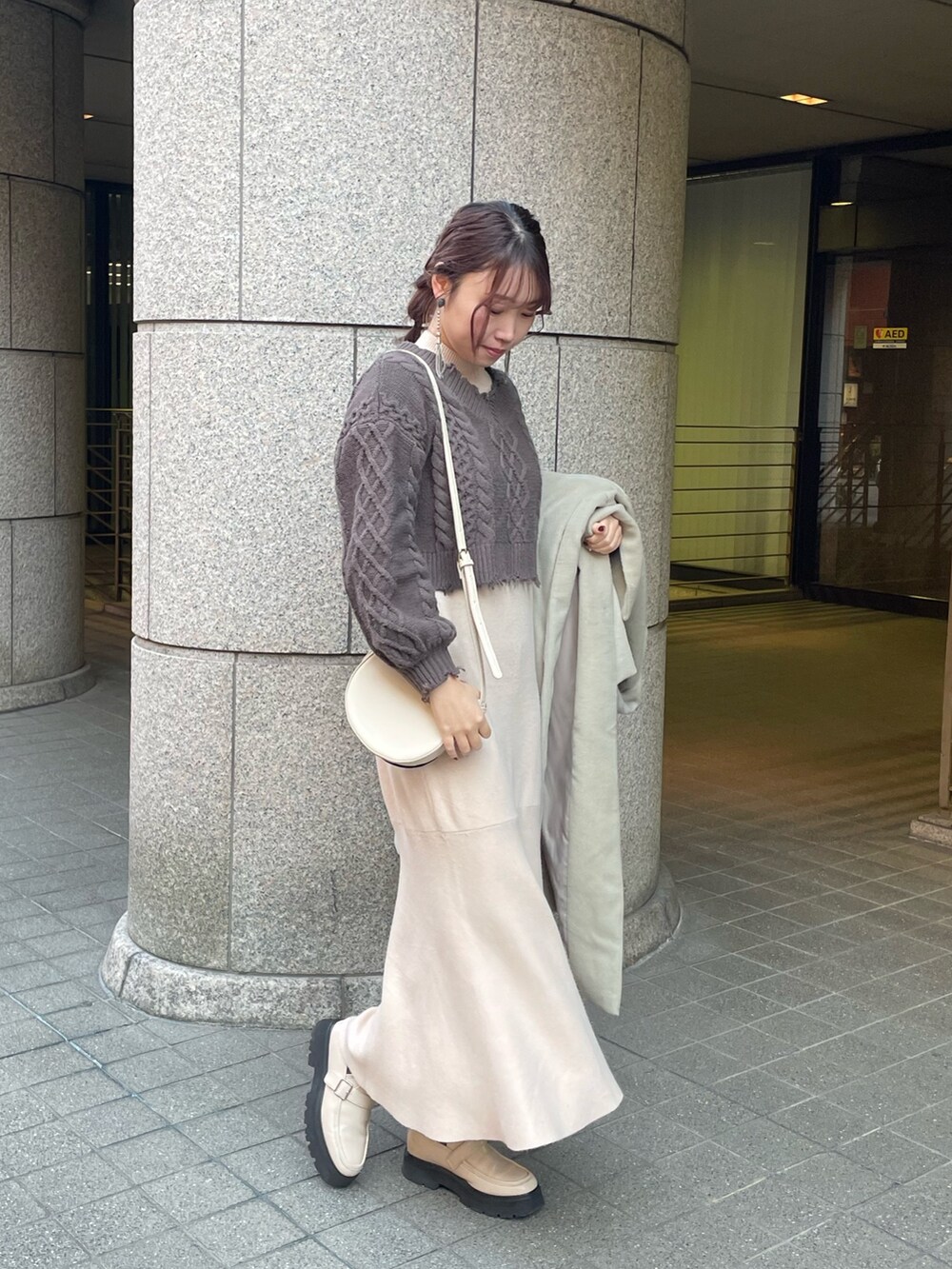 グリーン系のチェスターコート、ホワイト系のワンピースを着用したレディースの冬コーディネートの3枚目の写真