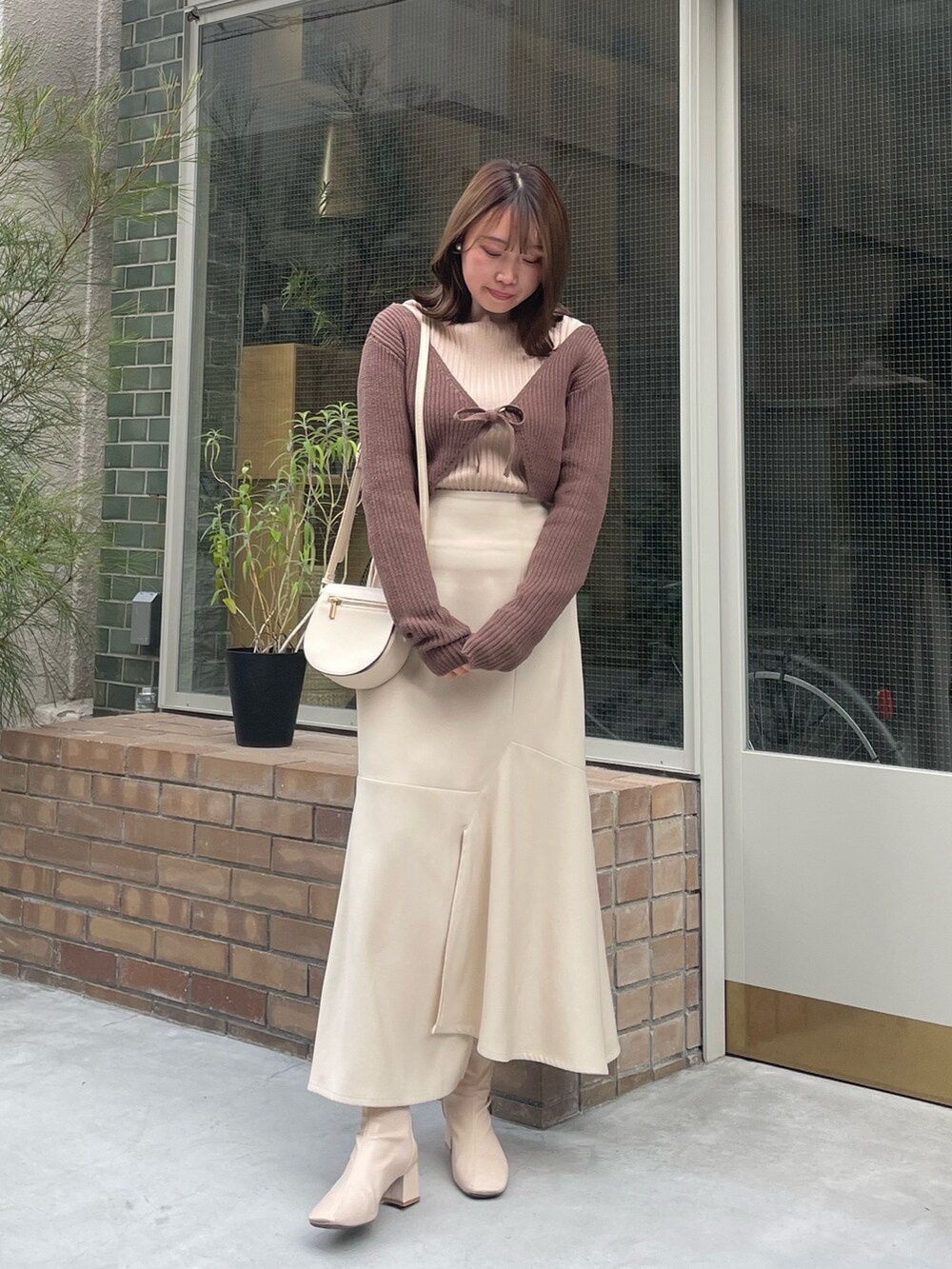 ホワイト系のスカート、ベージュ系のニット/セーター、ブラウン系のニット/セーターを着用したレディースの秋コーディネートの2枚目の写真