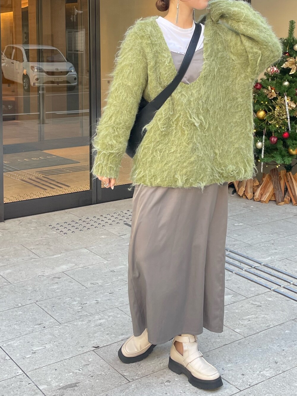 グリーン系のニット/セーター、ホワイト系のブーツを着用したレディースの秋コーディネートの3枚目の写真