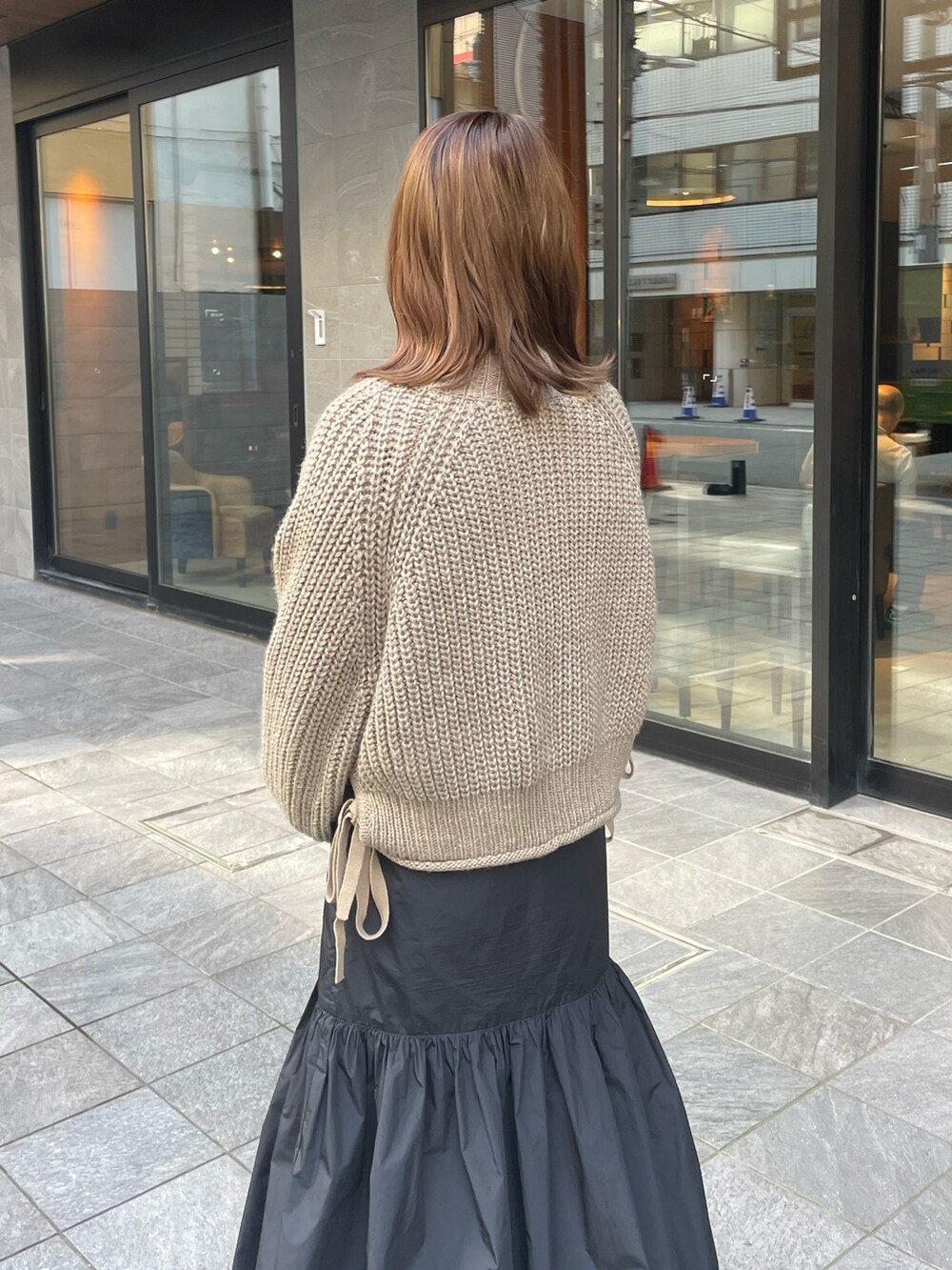 ベージュ系のニット/セーター、ブラック系のワンピース/ドレス、ホワイト系のブーツを着用したレディースの秋コーディネートの4枚目の写真