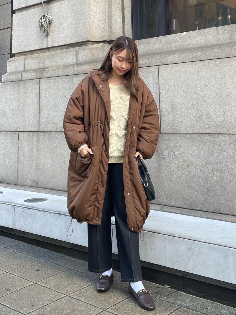 ブラック系のデニムパンツ、ブラウン系のダウンジャケット/コート、ホワイト系のニット/セーターを着用したレディースの秋コーディネートの2枚目の写真