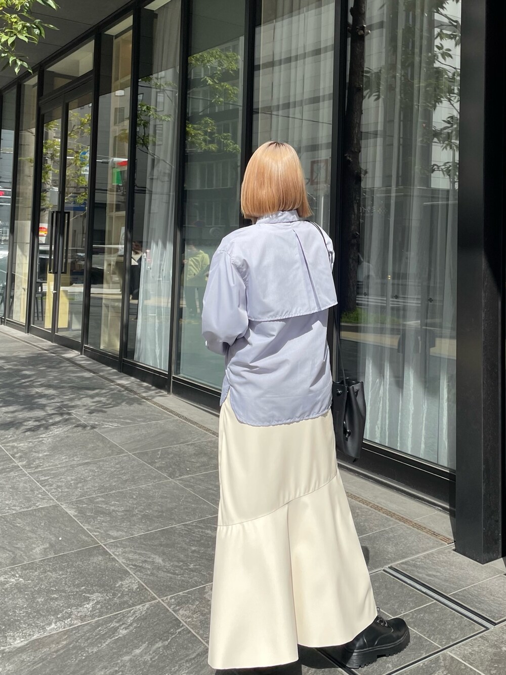 ブルー系のシャツ/ブラウス、ブラック系のバッグ、ホワイト系のスカートを着用したレディースの春コーディネートの2枚目の写真