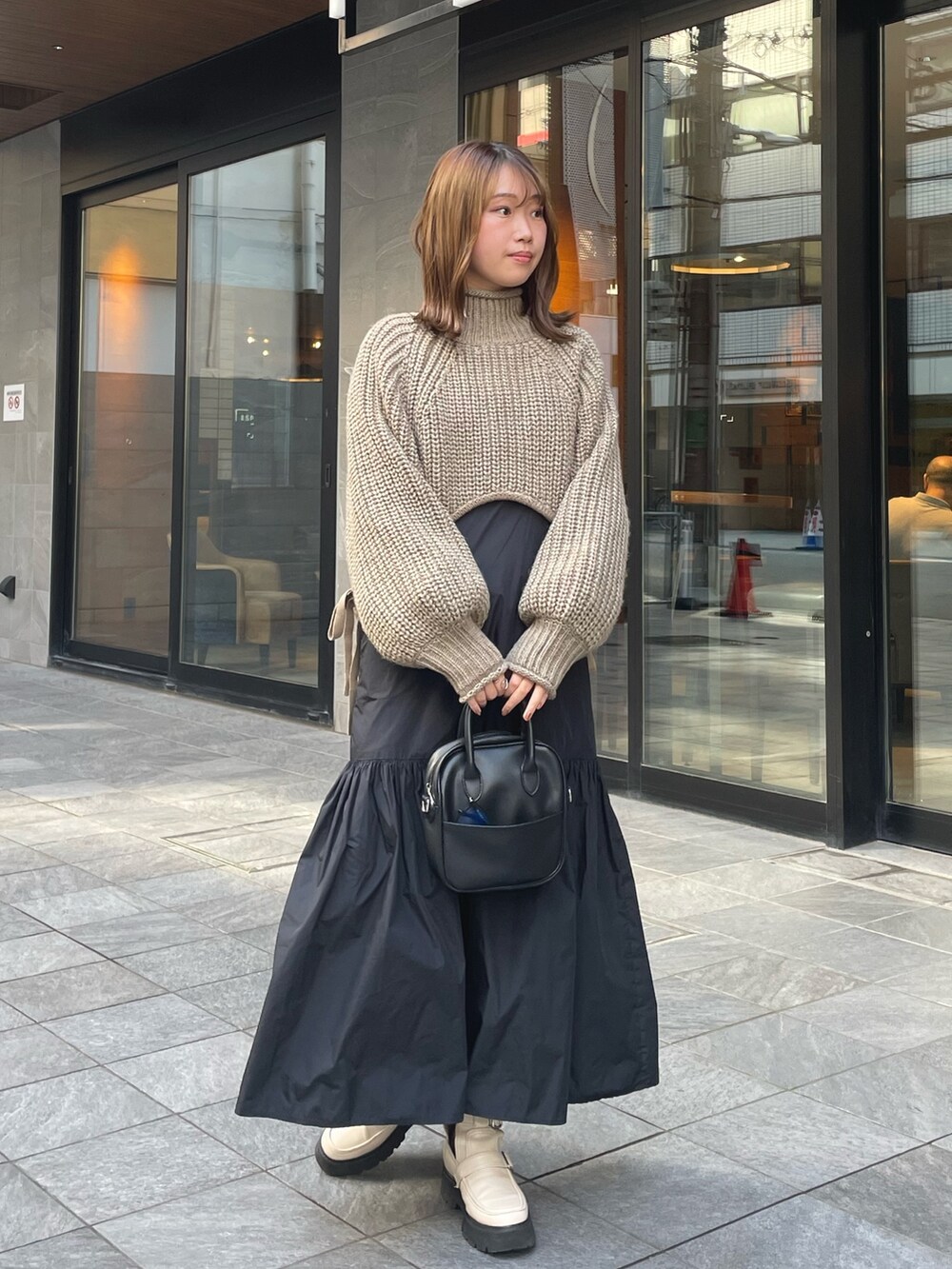 ベージュ系のニット/セーター、ブラック系のワンピース/ドレス、ホワイト系のブーツを着用したレディースの秋コーディネートの3枚目の写真