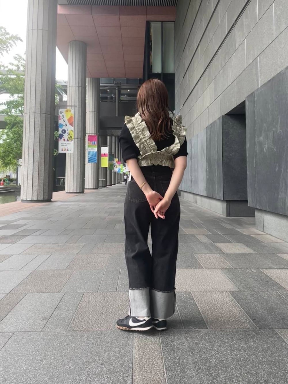 ブラック系のニット/セーター、ベージュ系のベスト、ブラック系のデニムパンツを着用したレディースの夏コーディネートの3枚目の写真