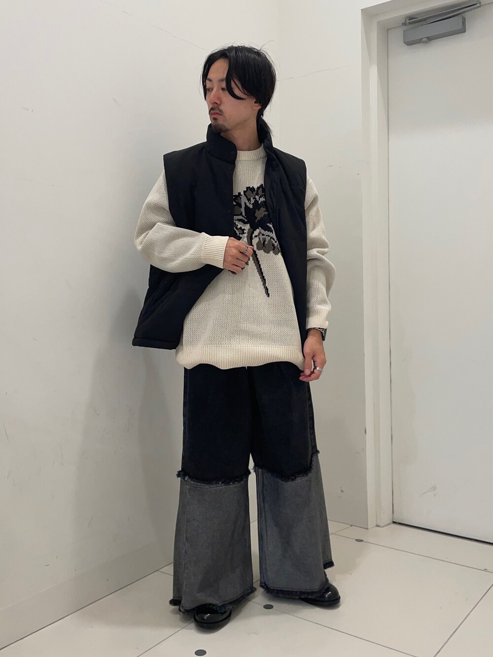 ブルー系のデニムパンツ、ブラック系のダウンベスト、ホワイト系のニット/セーターを着用したメンズの冬コーディネートの2枚目の写真