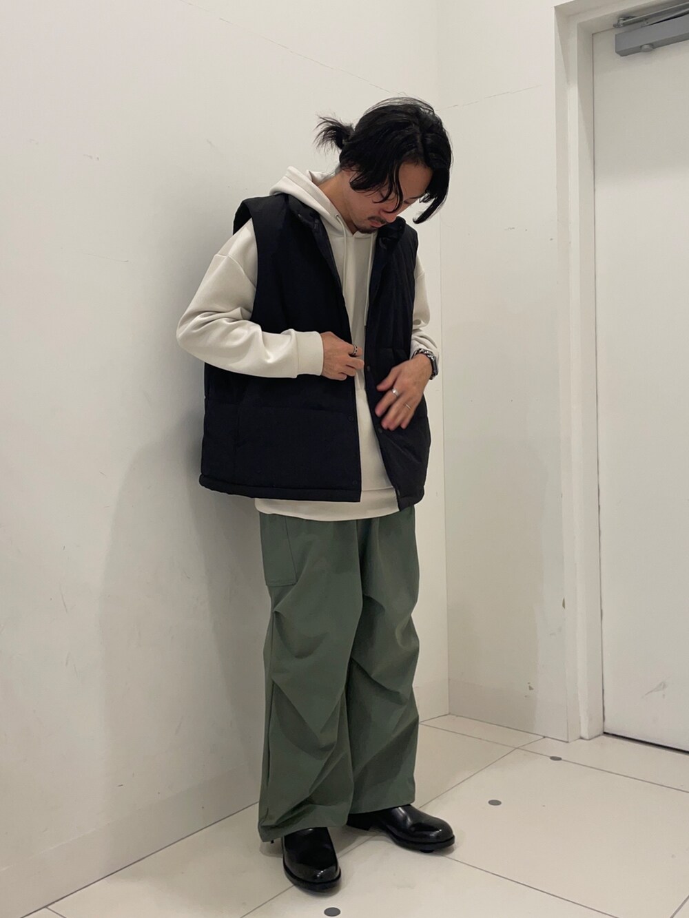 ブラック系のダウンベスト、ベージュ系のパーカー、グリーン系のカーゴパンツを着用したメンズの秋コーディネートの2枚目の写真