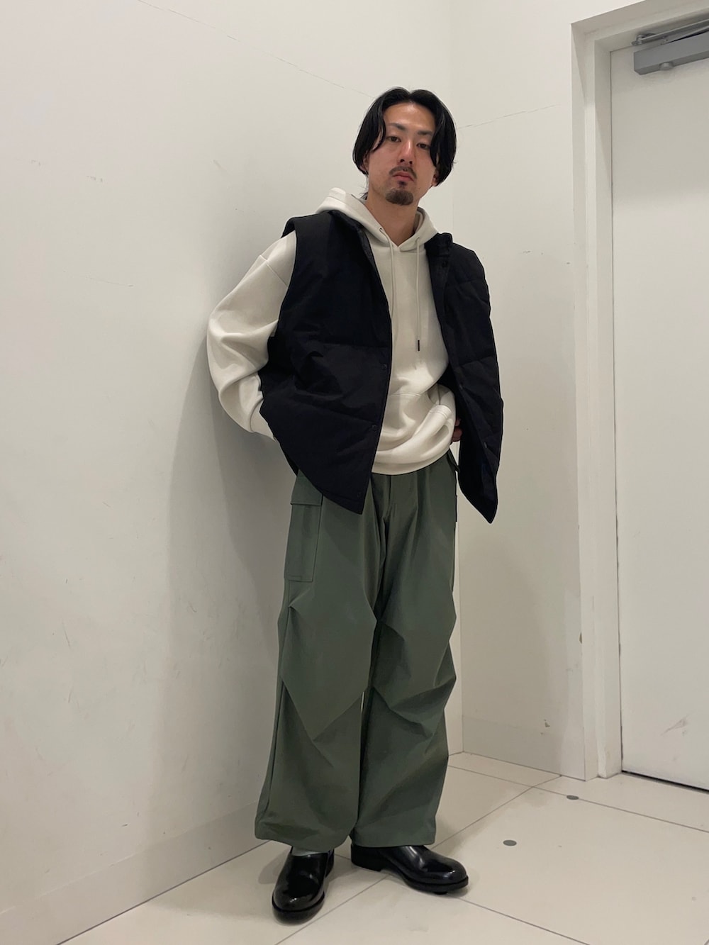 ブラック系のダウンベスト、ブラック系のパーカー、グリーン系のカーゴパンツを着用したメンズの冬コーディネートの2枚目の写真
