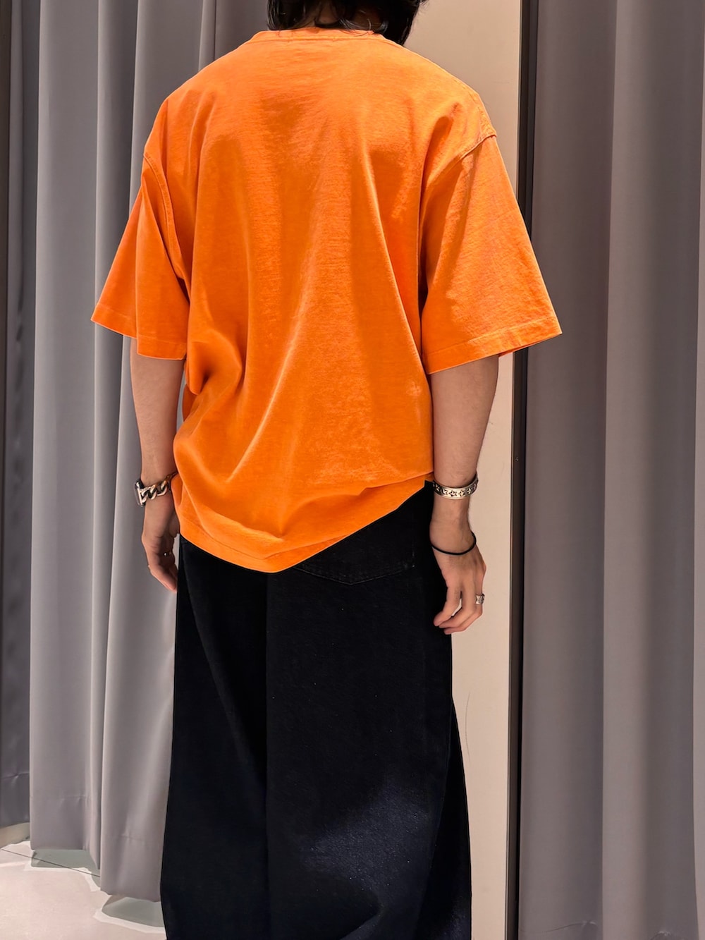 オレンジ系のTシャツ/カットソー、ブルー系のデニムパンツを着用したメンズの夏コーディネートの3枚目の写真