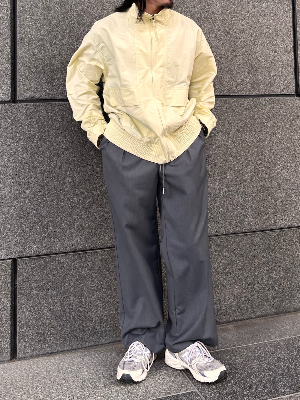 イエロー系のブルゾン、グレー系のスラックスを着用したメンズの春コーディネートの4枚目の写真