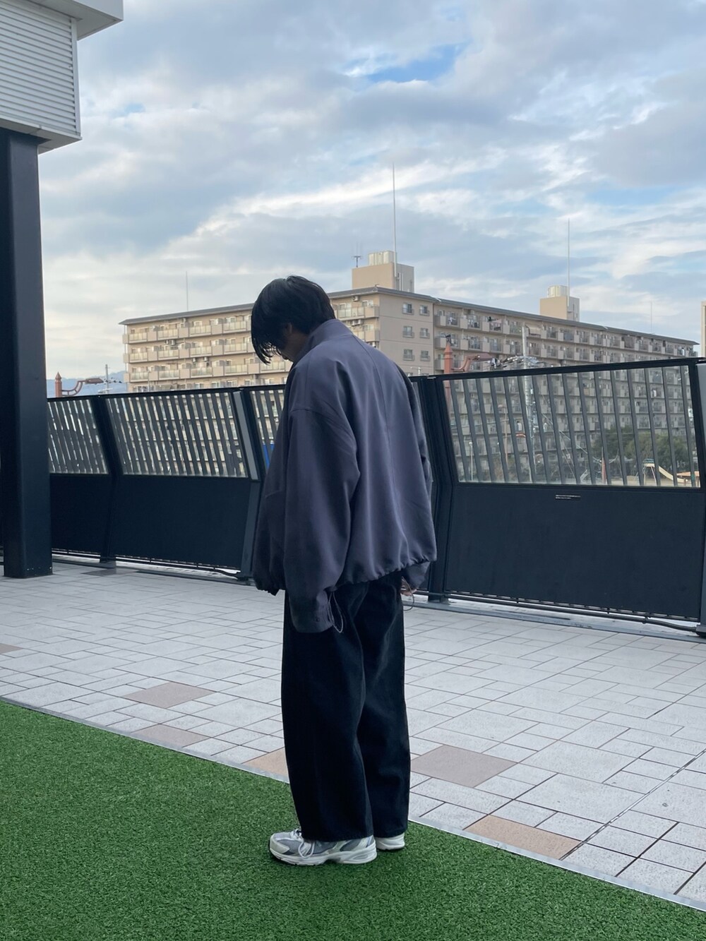 ブルー系のモッズコート、ブラック系のデニムパンツ、ブラック系のニット/セーターを着用したメンズの春コーディネートの2枚目の写真