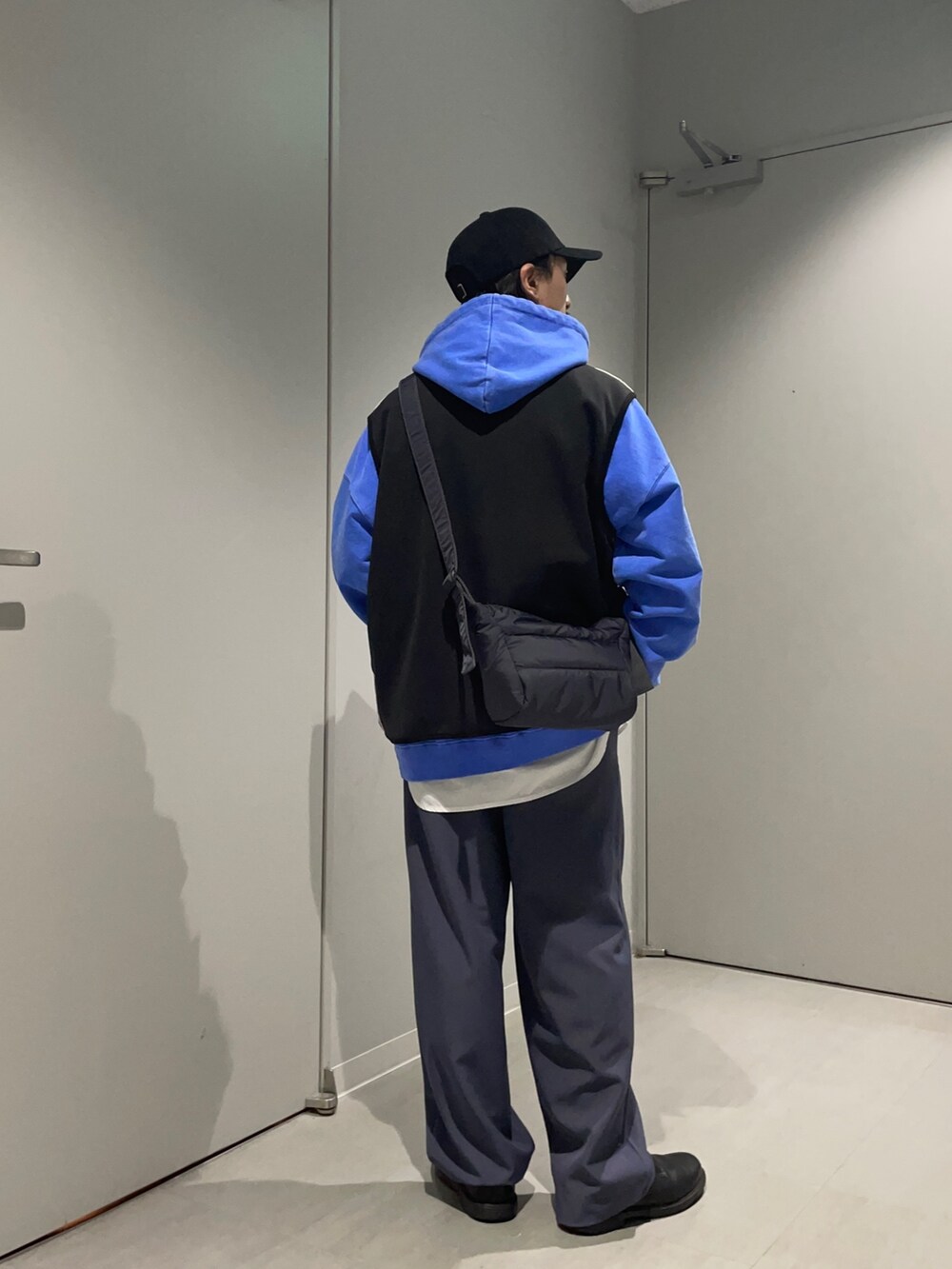 グレー系のショルダーバッグ、ブラック系のベスト、ブルー系のその他パンツを着用したメンズの春コーディネートの2枚目の写真