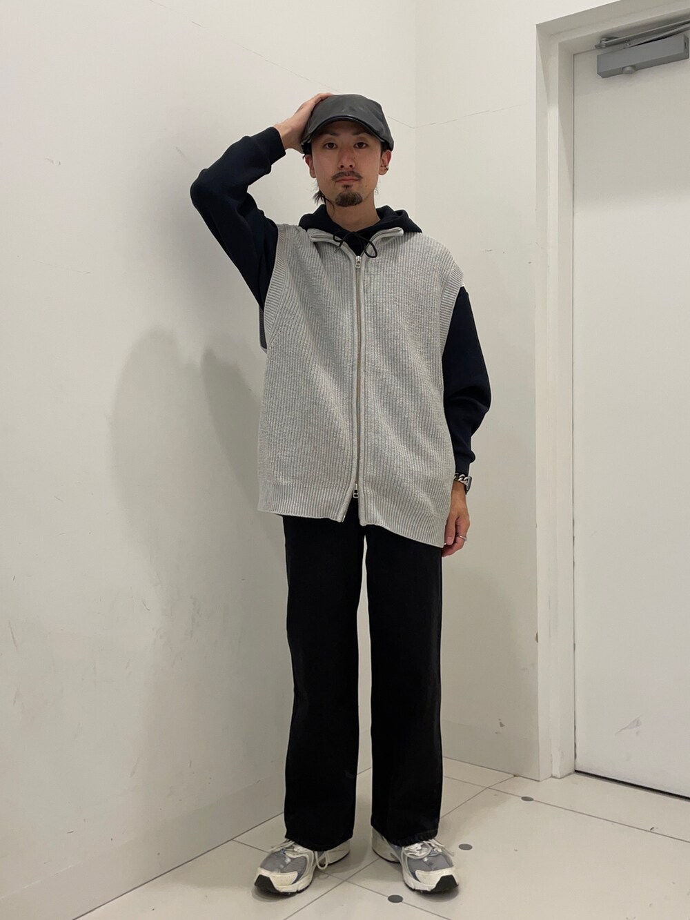 グレー系のベスト、ブラック系のスラックス、ブラック系のパーカーを着用したメンズの秋コーディネートの2枚目の写真