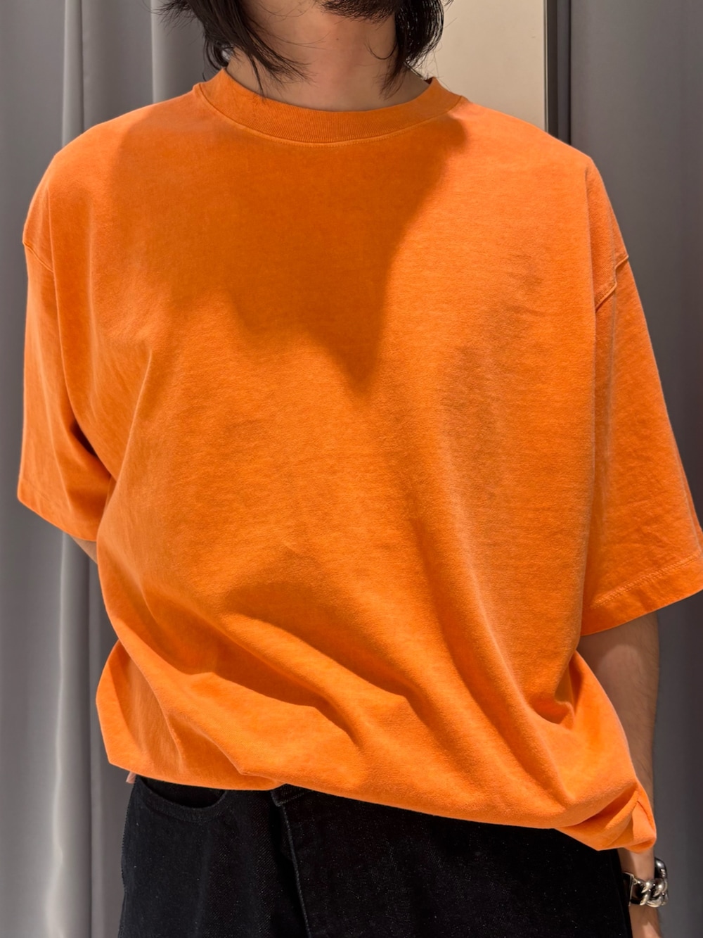 オレンジ系のTシャツ/カットソー、ブルー系のデニムパンツを着用したメンズの夏コーディネートの2枚目の写真