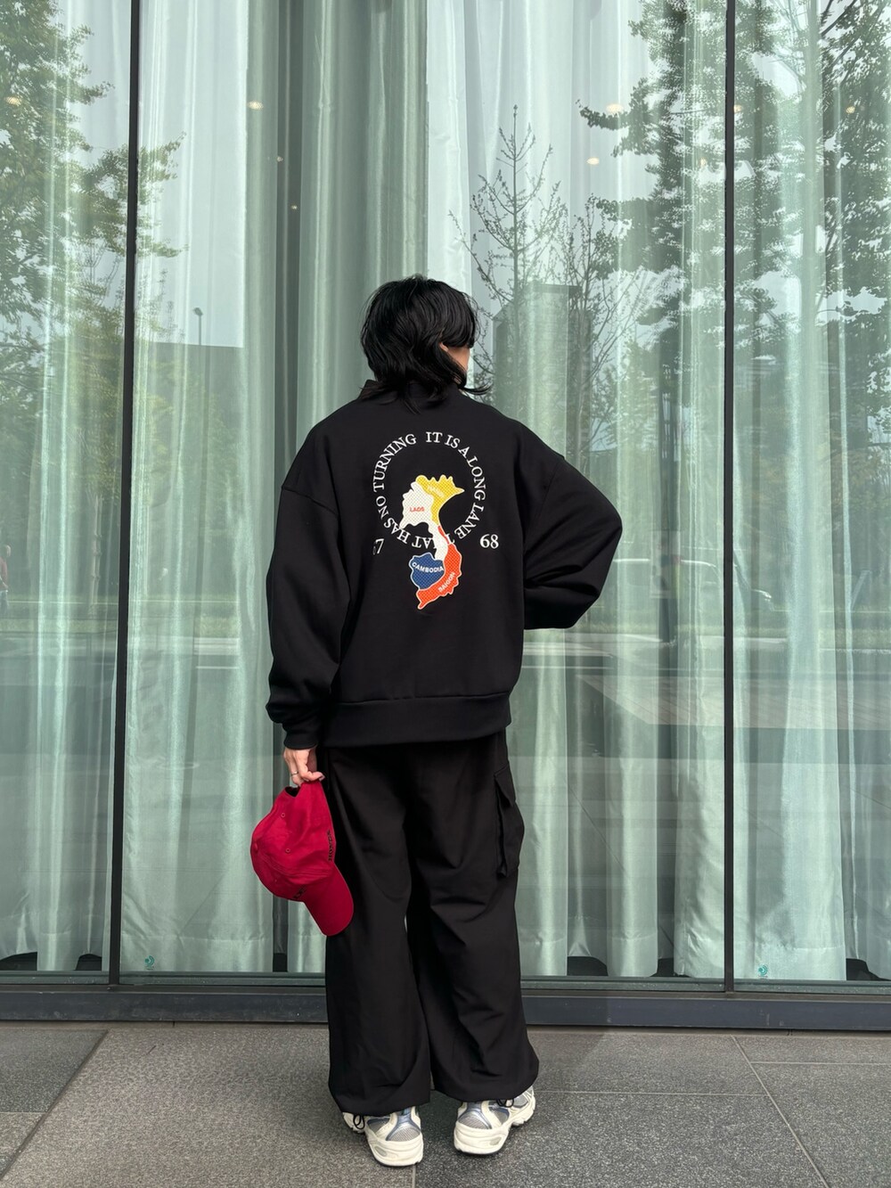 ブラック系のブルゾン、ブラック系のカーゴパンツ、レッド系のキャップを着用したメンズの秋コーディネートの2枚目の写真