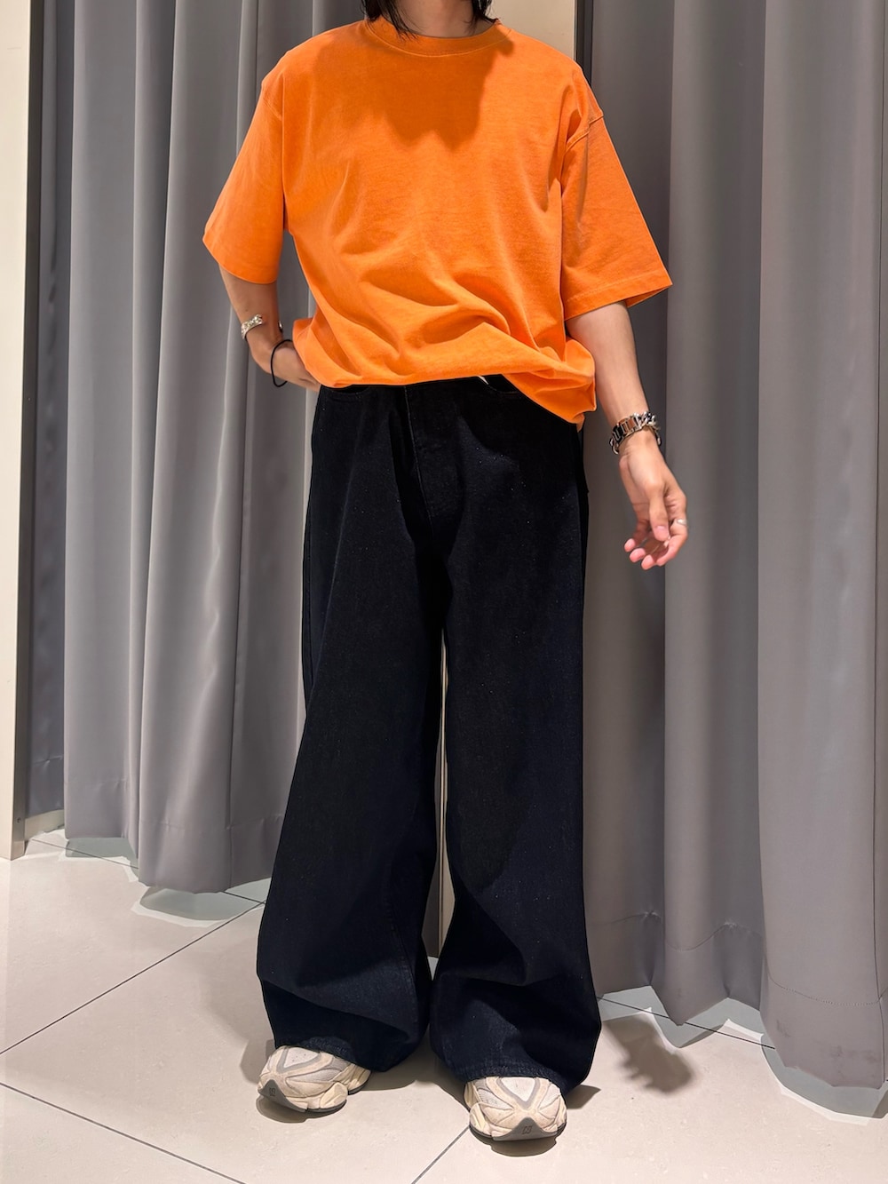 オレンジ系のTシャツ/カットソー、ブルー系のデニムパンツを着用したメンズの夏コーディネートの4枚目の写真