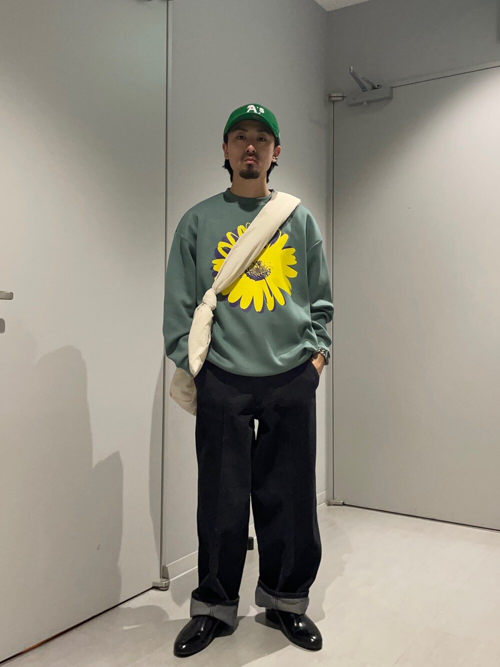 グリーン系のスウェット、ブラック系のデニムパンツ、グリーン系のショルダーバッグを着用したメンズの春コーディネートの3枚目の写真