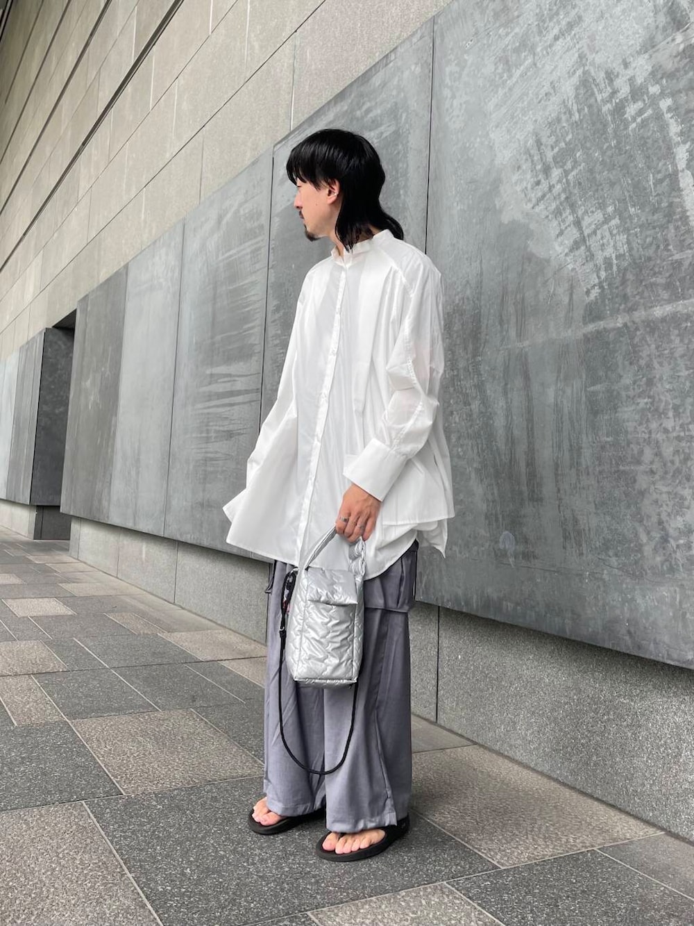 グレー系のカーゴパンツ、ホワイト系のワンピース、シルバー系のハンドバッグを着用したメンズの夏コーディネートの3枚目の写真