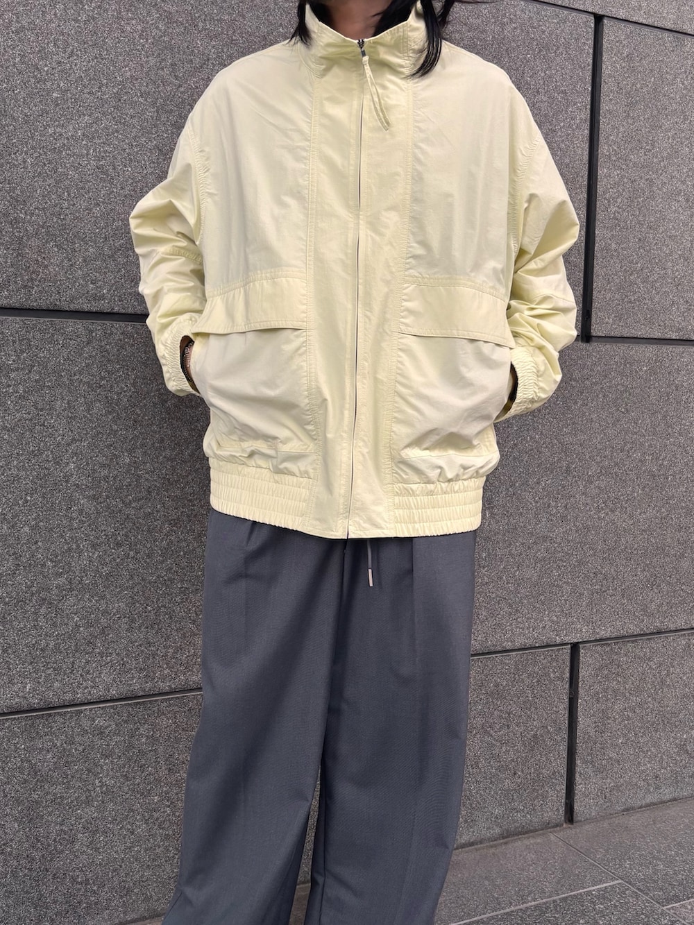 イエロー系のブルゾン、グレー系のスラックスを着用したメンズの春コーディネートの2枚目の写真