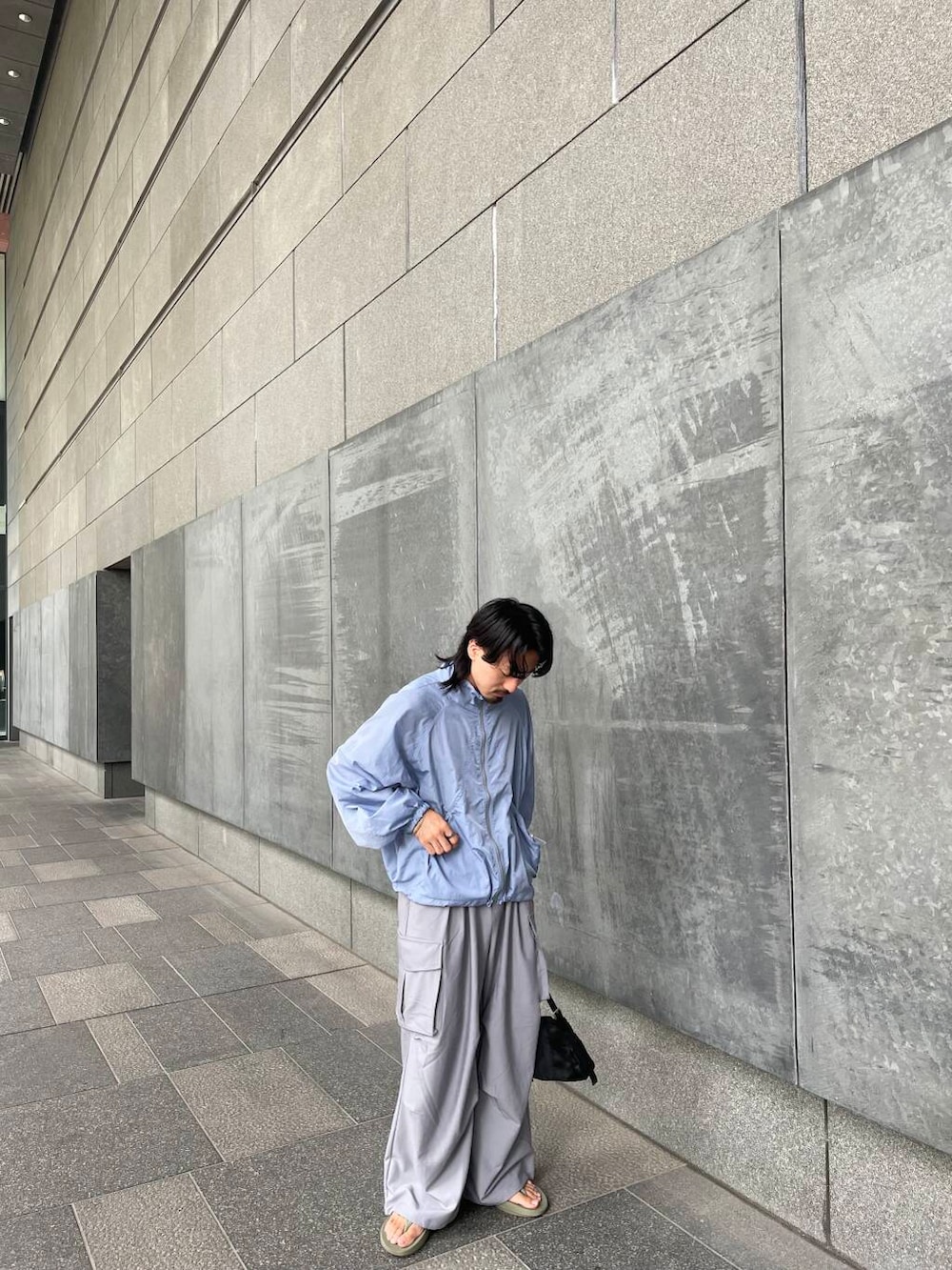 グレー系のショルダーバッグ、ブルー系のナイロンジャケット、グレー系のカーゴパンツを着用したメンズの秋コーディネートの2枚目の写真