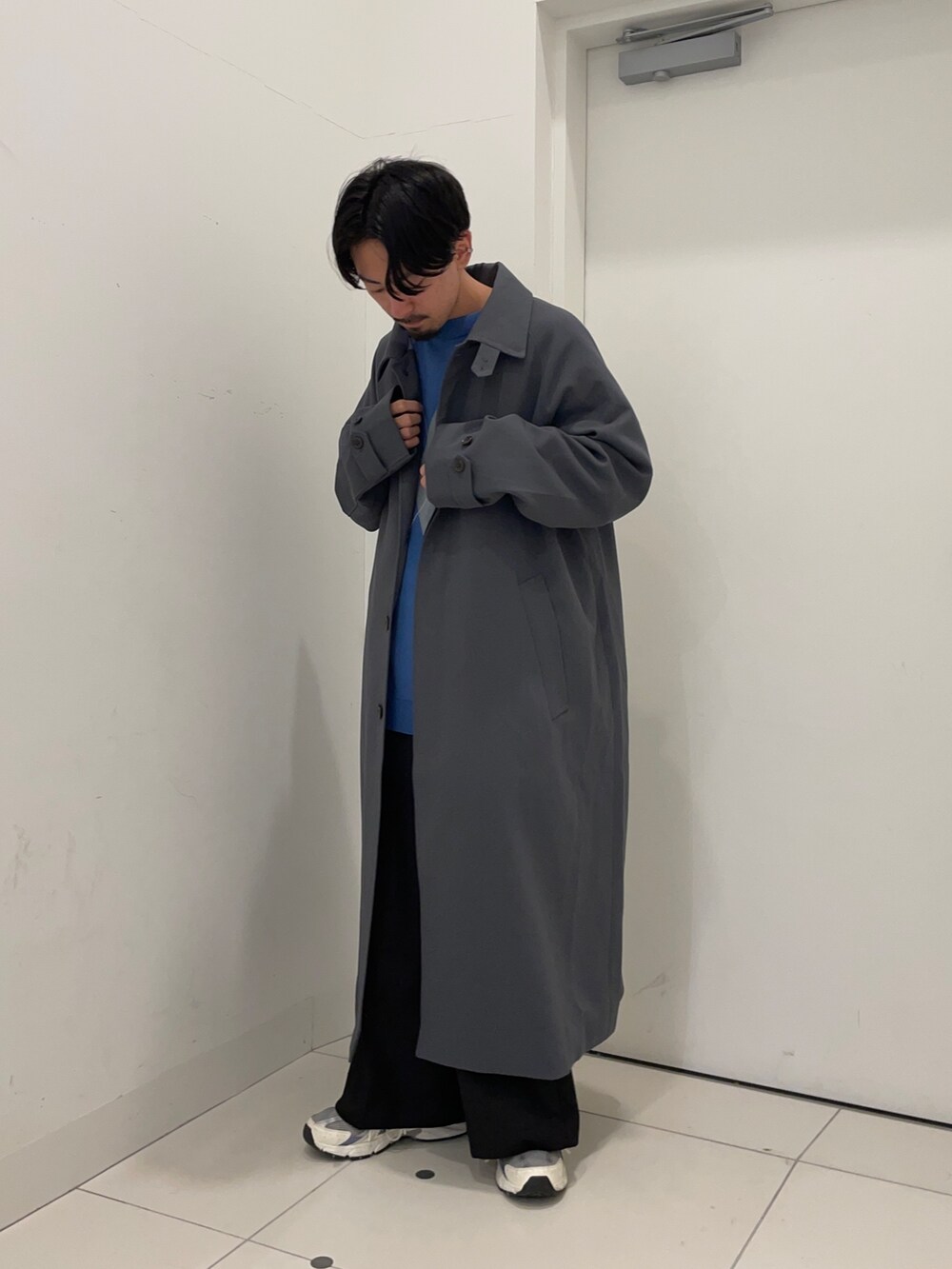 ブラック系のスラックス、ブルー系のニット/セーター、ブルー系のステンカラーコートを着用したメンズの冬コーディネートの2枚目の写真