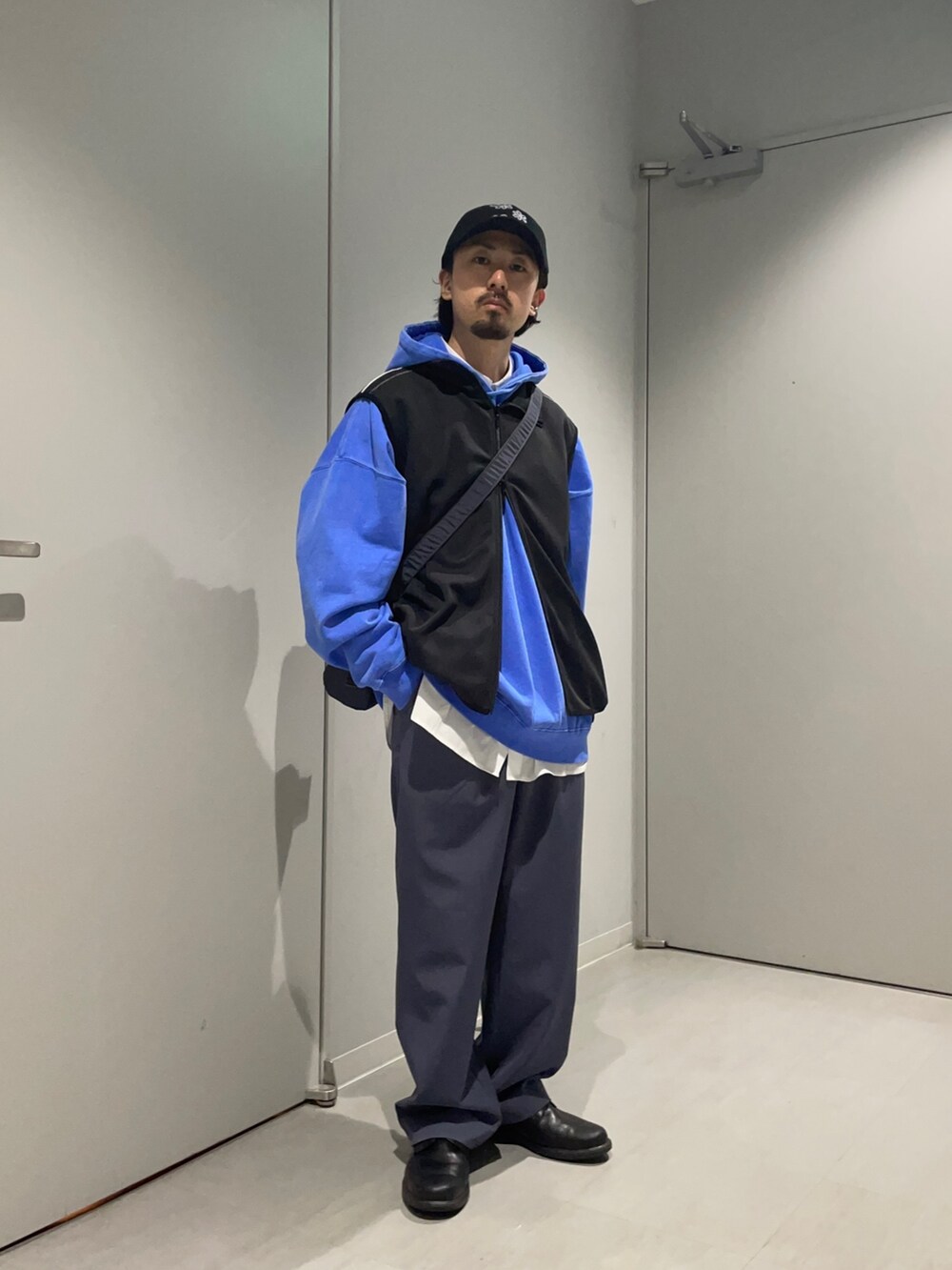 グレー系のショルダーバッグ、ブラック系のベスト、ブルー系のその他パンツを着用したメンズの春コーディネートの3枚目の写真