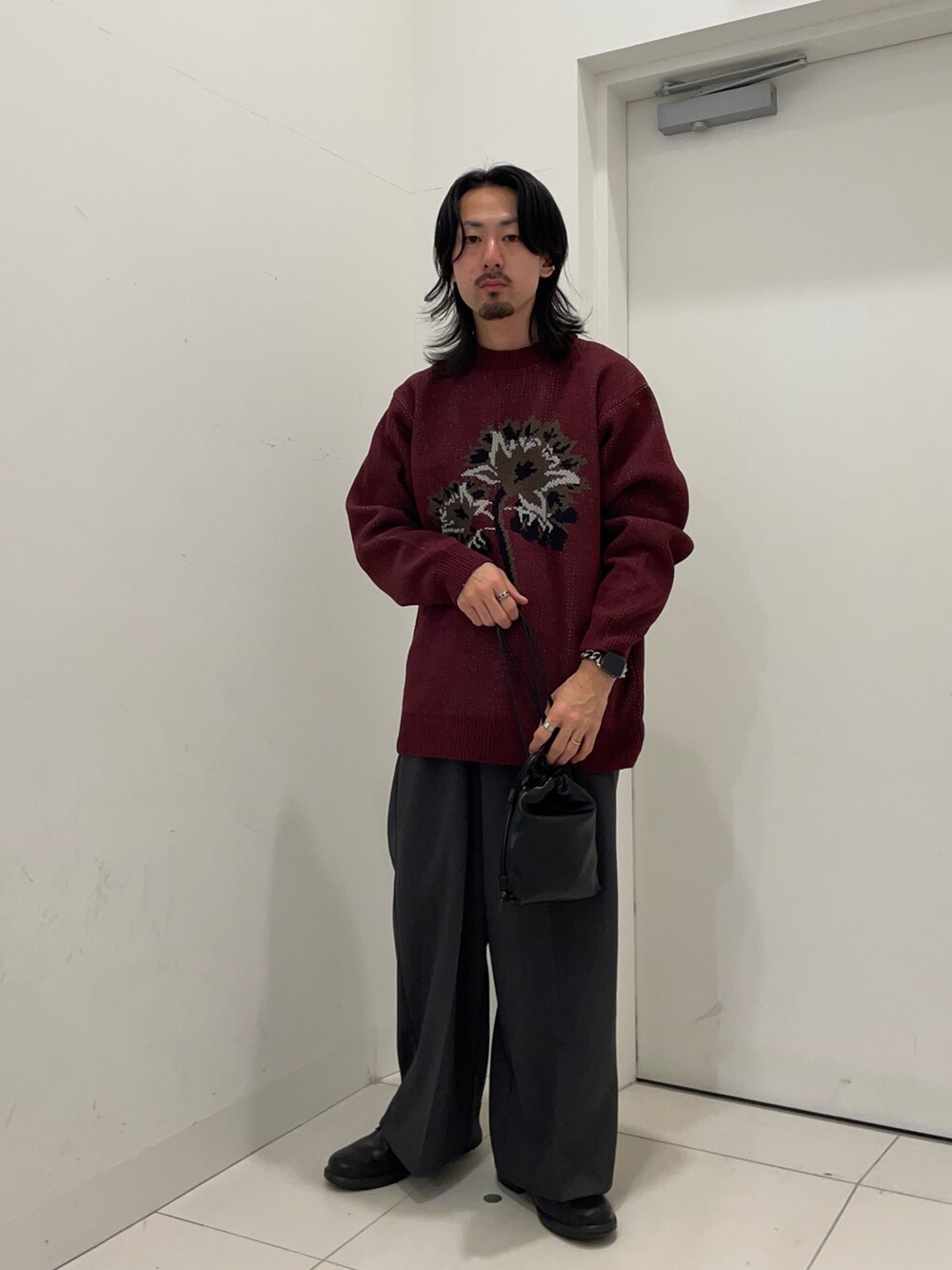 レッド系のニット/セーター、グレー系のその他パンツを着用したメンズの秋コーディネートの2枚目の写真