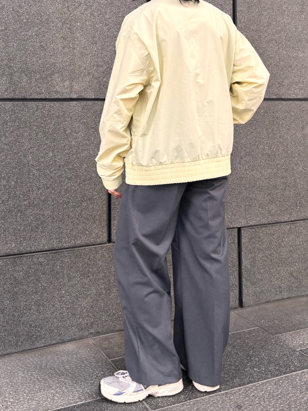 イエロー系のブルゾン、グレー系のスラックスを着用したメンズの春コーディネートの3枚目の写真