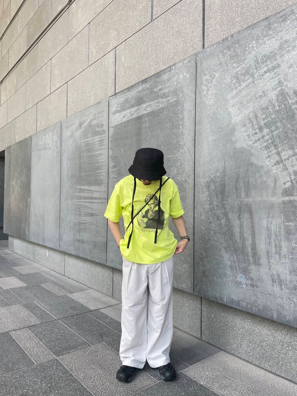 ベージュ系のその他パンツ、イエロー系のTシャツ/カットソー、ブラック系のハットを着用したメンズの夏コーディネートの3枚目の写真