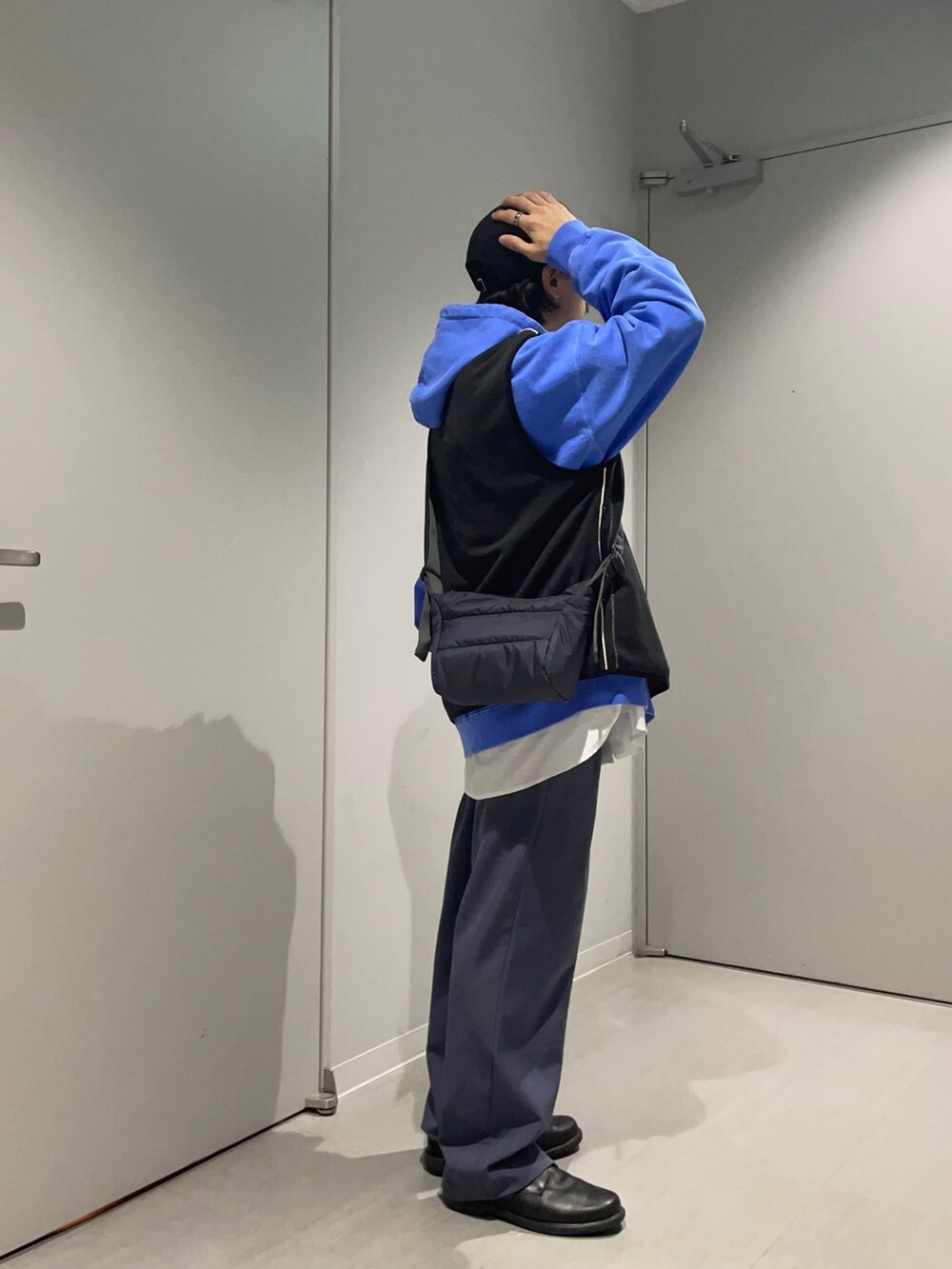 グレー系のショルダーバッグ、ブラック系のベスト、ブルー系のその他パンツを着用したメンズの春コーディネートの4枚目の写真