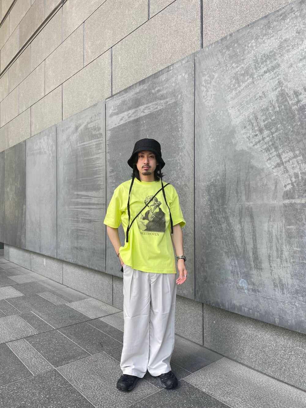 ベージュ系のその他パンツ、イエロー系のTシャツ/カットソー、ブラック系のハットを着用したメンズの夏コーディネートの2枚目の写真