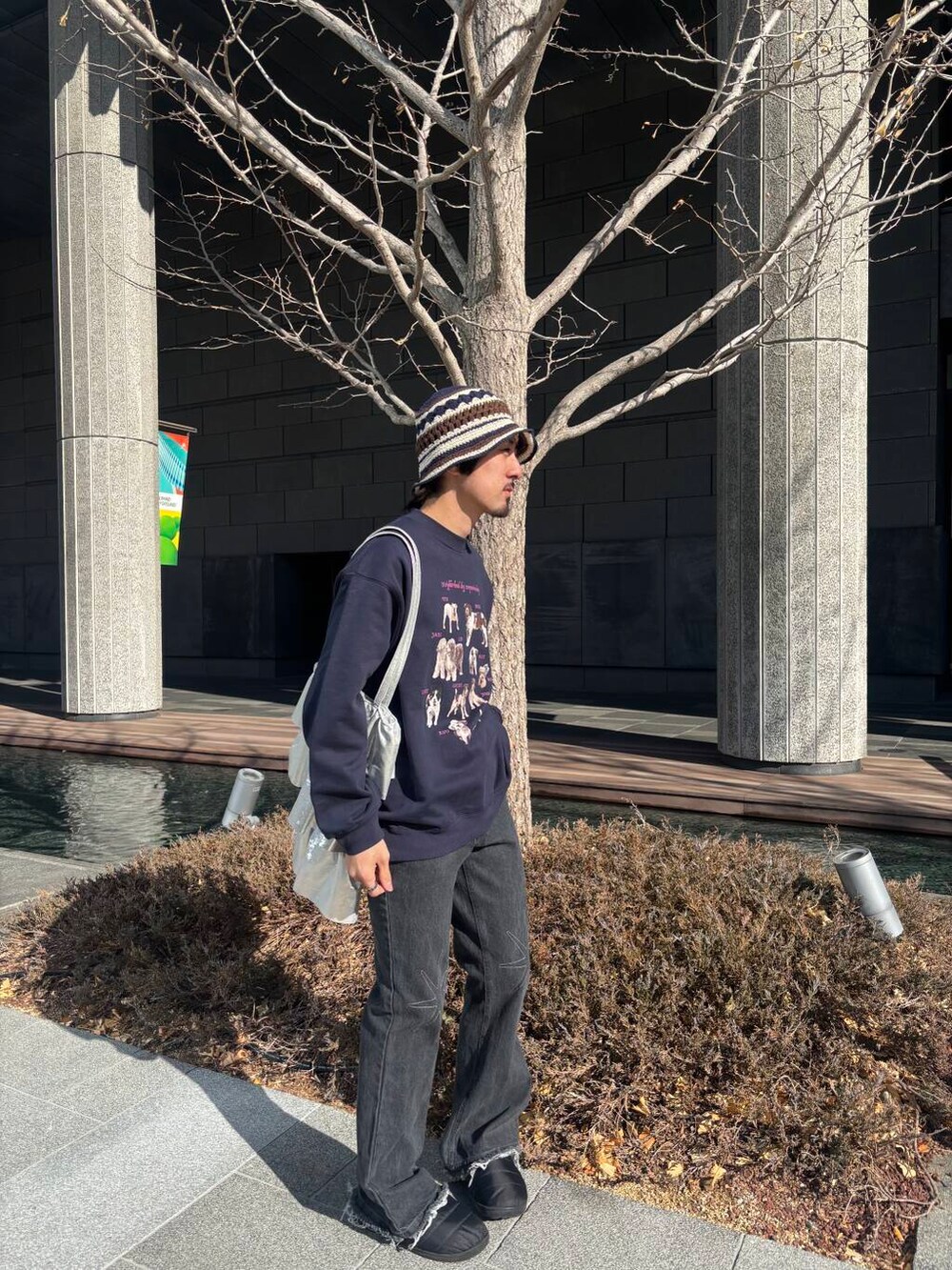 ゴールド系のトートバッグ、ブルー系のスウェット、ブラック系のデニムパンツを着用したメンズの冬コーディネートの2枚目の写真